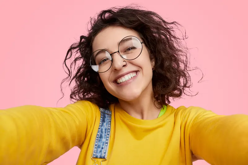 Junge Frau mit runder Brille macht ein Selfie